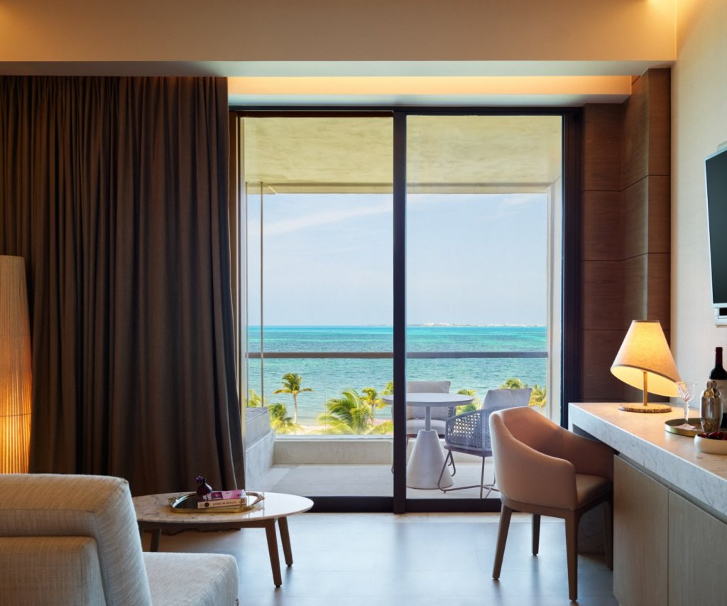 the inside of a room looking out to a terrace with a beautiful view of the ocean