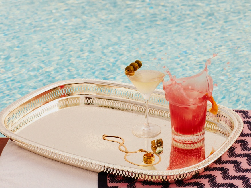 two elaborate cocktails on a silver tray by the pool