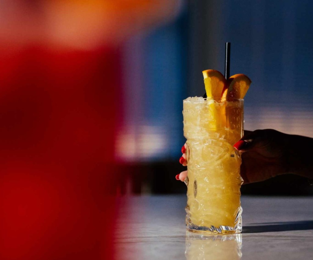 A refreshing citrus cocktail sits across a red cocktail