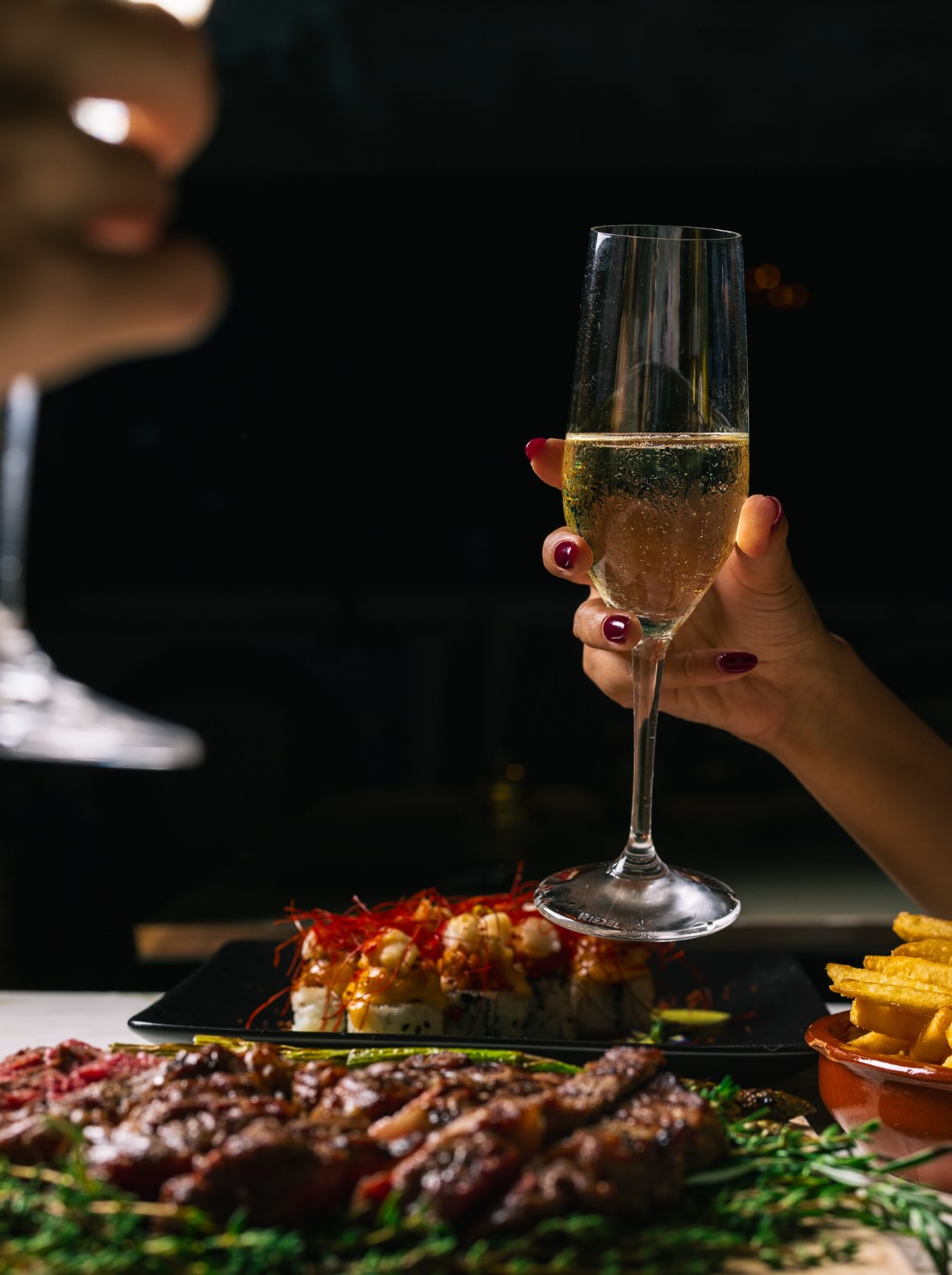 a hand holding a glass of champagne over delectable bites