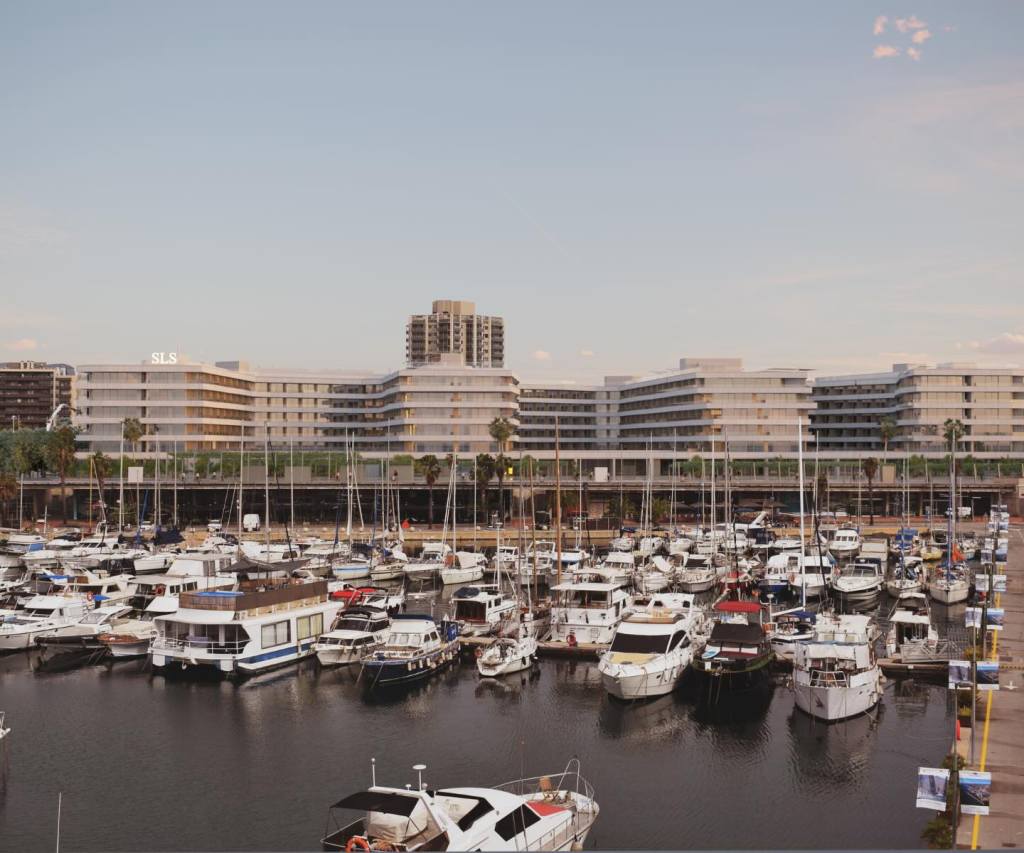 the waterfront sls barcelona resort behind a marina filled with sail boats