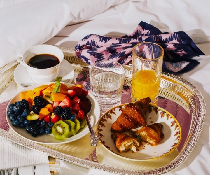 A breakfast platter sits on the bed at SLS LUX Brickell