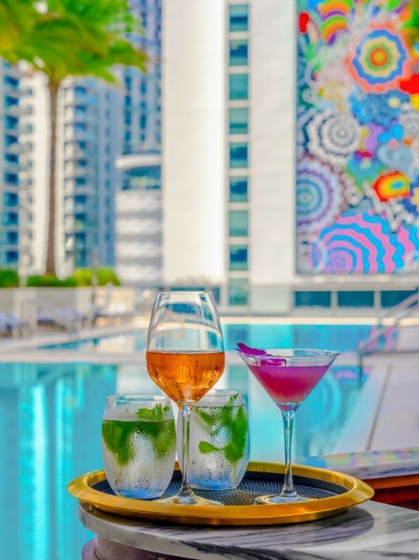 Two cocktails with waters sit looking refreshing by Altitude Pool & Lounge's pool