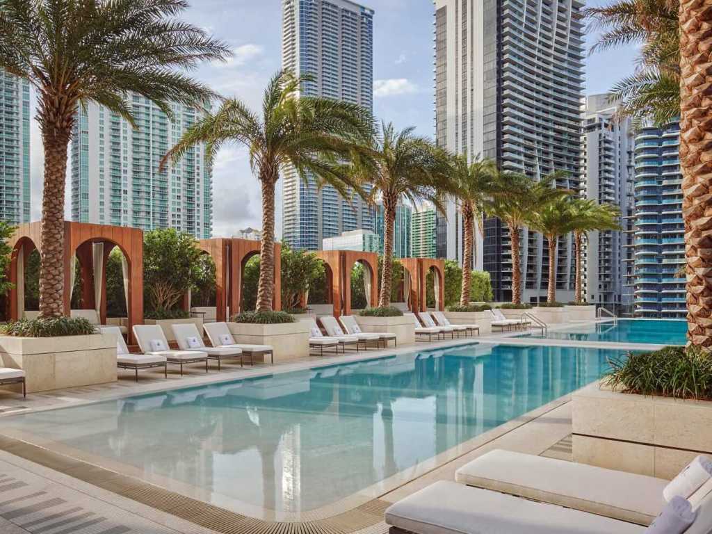 a luxurious pool at sls brickell with palm trees and cabanas