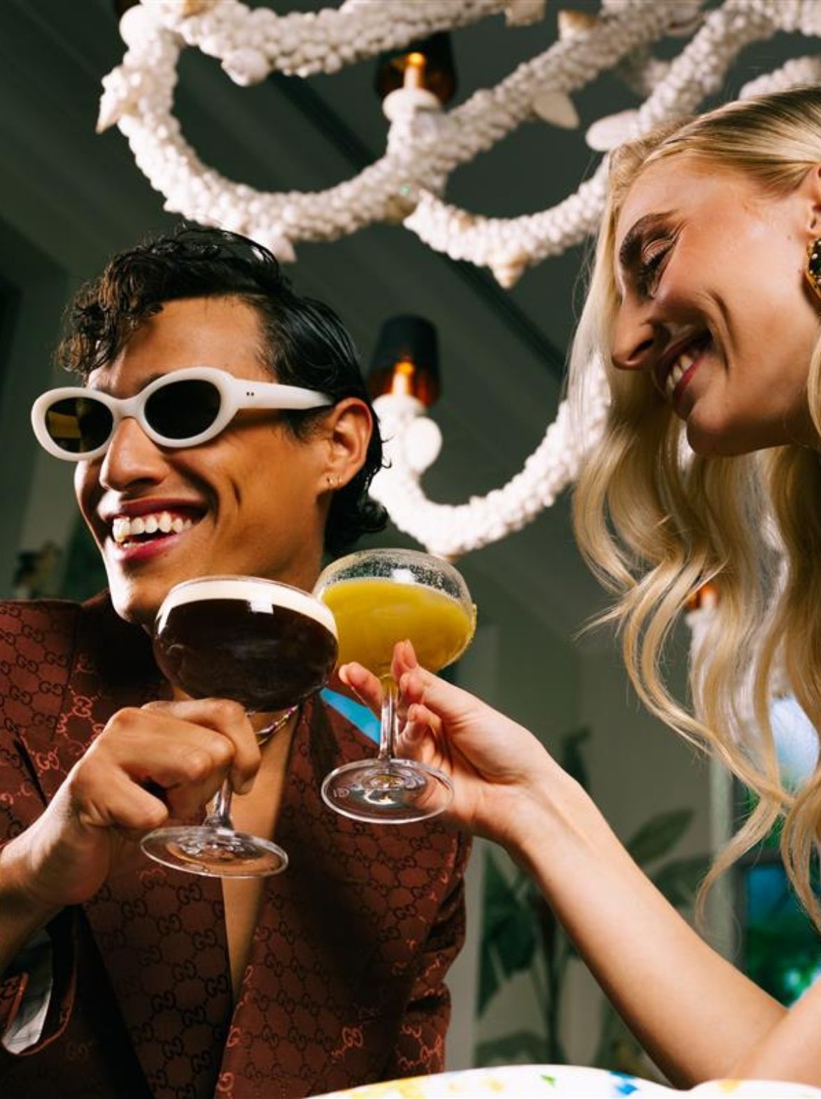 A male and female model clink their glasses together in celebration