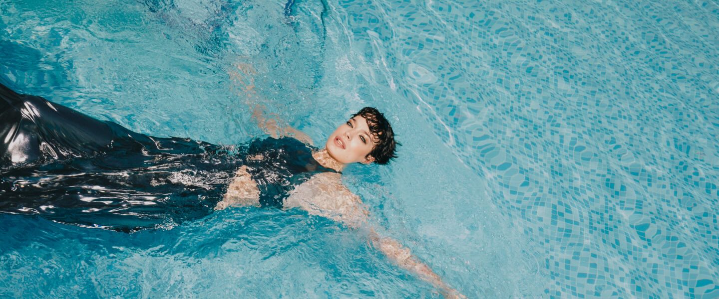 a woman in an elegant dress swimming in a pool