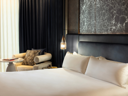 a guest room at sls barcelona with a blue headboard and bedside chair