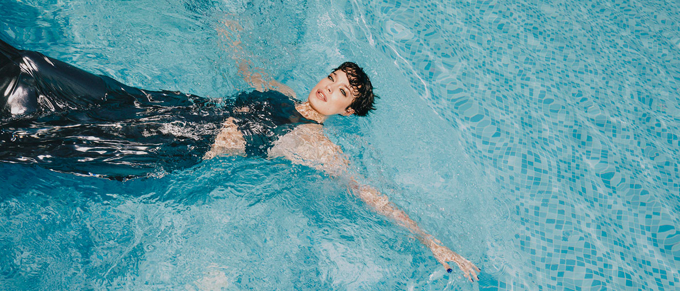 Woman swimming in a pool wearing a silver dress