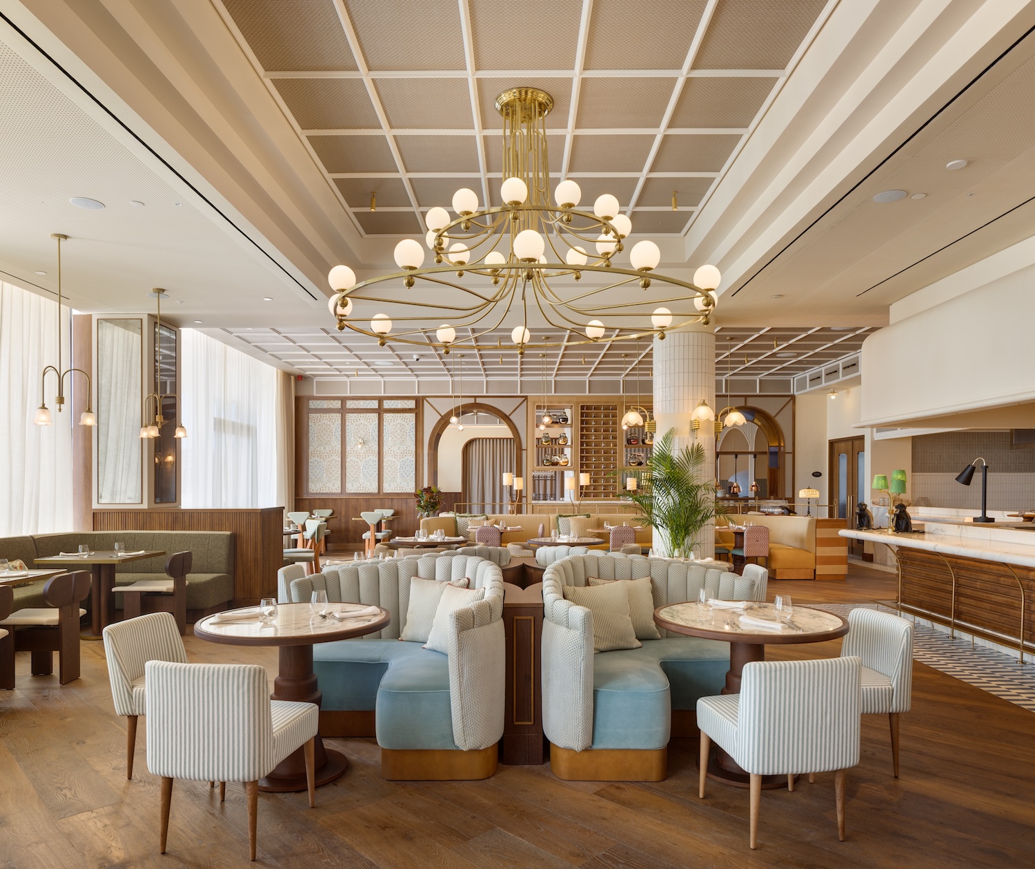 a restaurant space with green booths and chandeliers