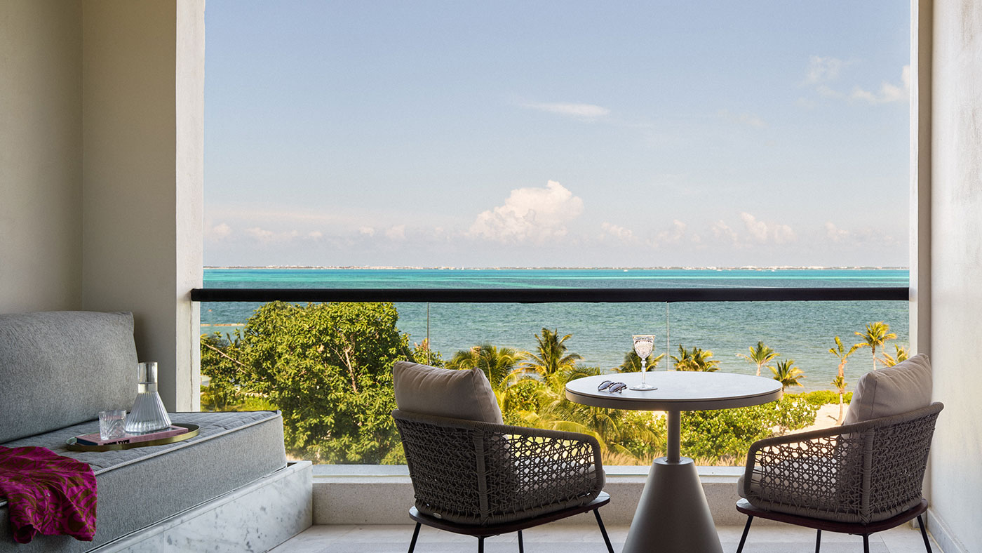 a patio off the room with a table, two chairs and plush lounge area with stunning ocean views
