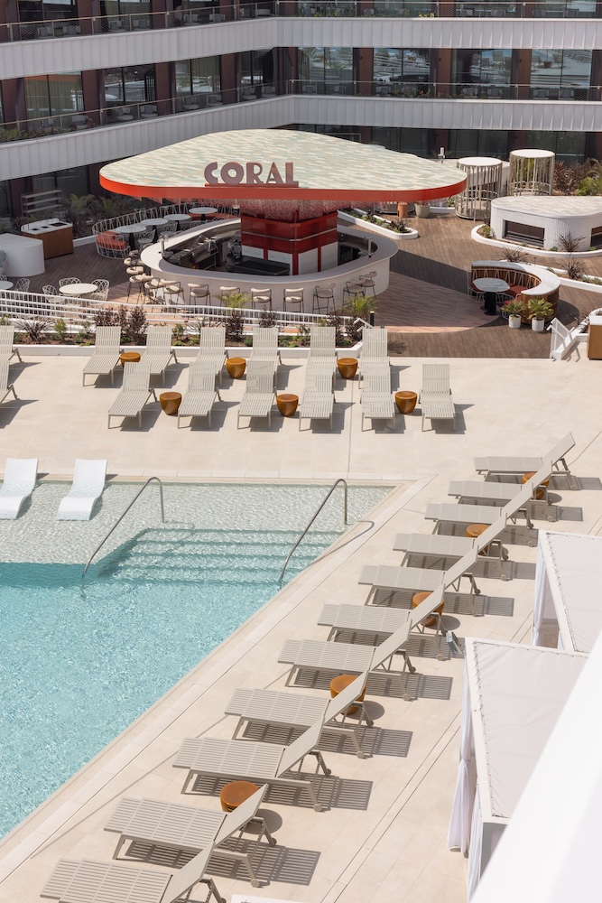 Pool with white sun loungers and an orange central bar