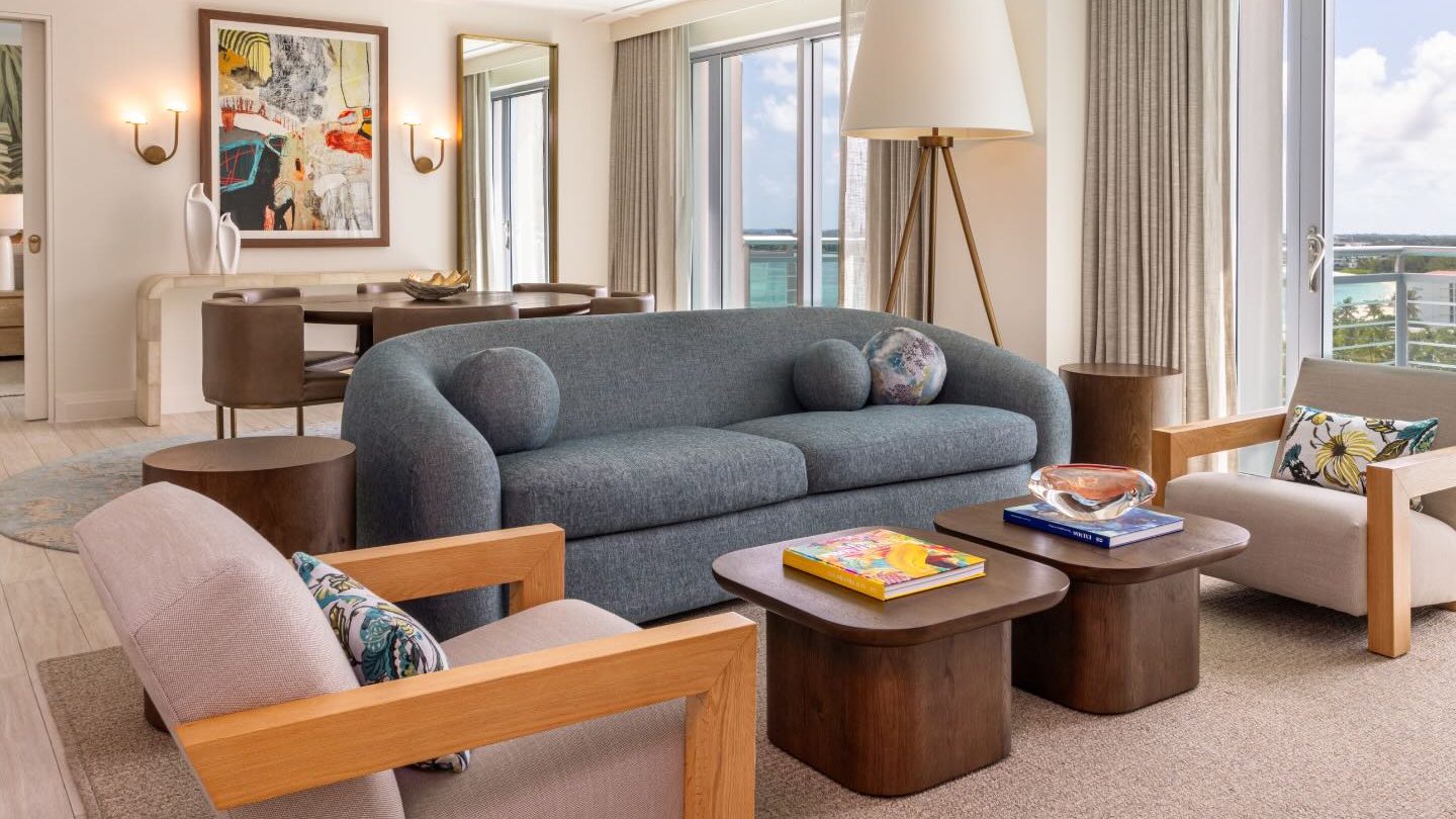 a living room with a seating area and pullout couch and a dining table behind it