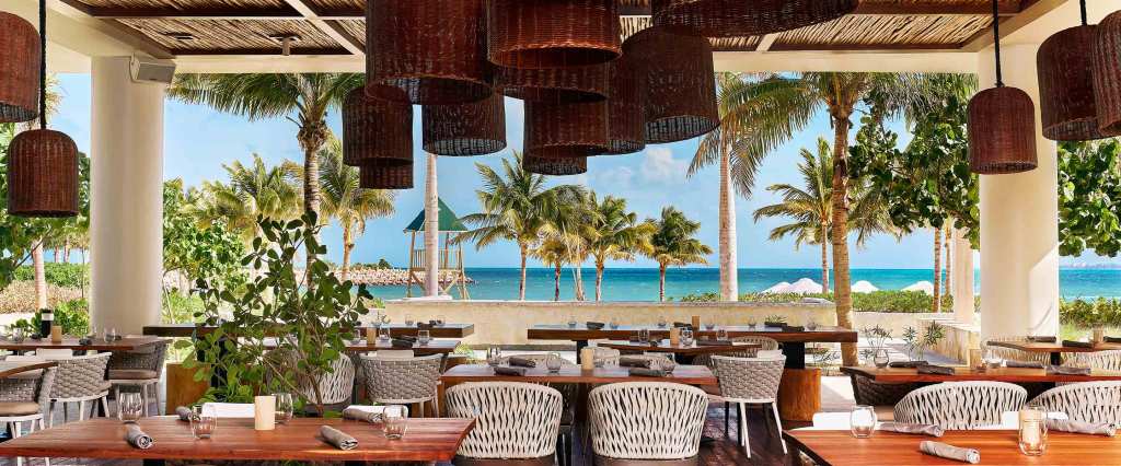 Outdoor beach restaurant with hanging wicker lanterns, looking out on the Caribbean Sea