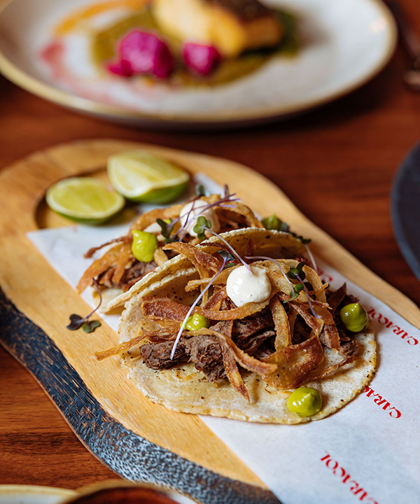 meat tacos on a plank board with limes 