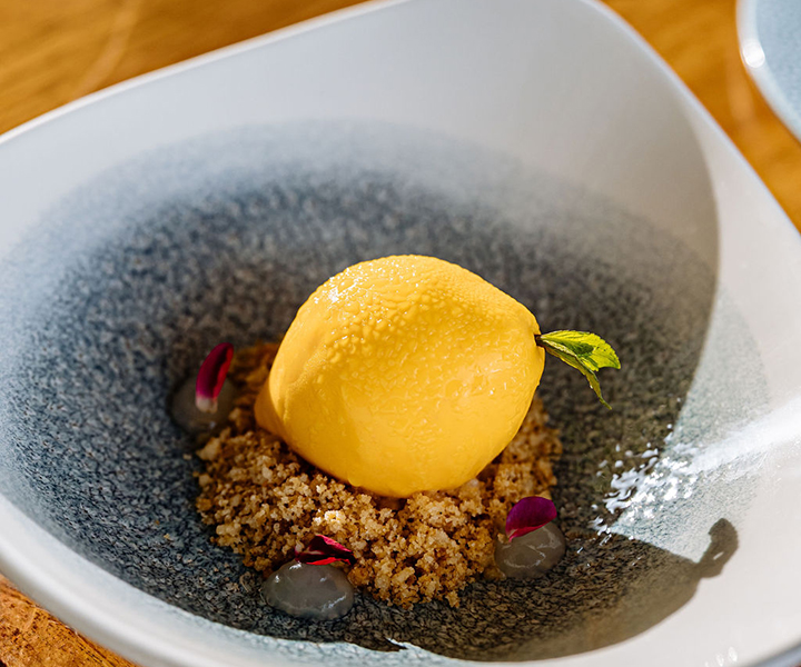 Italian lemon dessert styled to look like a real lemon, sitting atop almond and vanilla crisp