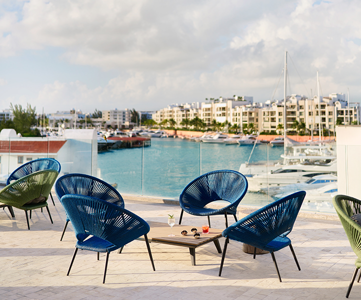 Four round blue outdoor chairs surrounding a table at an outdoor bar overlooking the marina