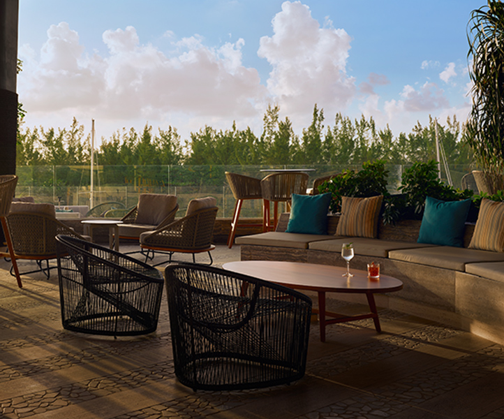 Outdoor bar at SLS Playa Mujeres bathed in dusk light, overlooking a marina