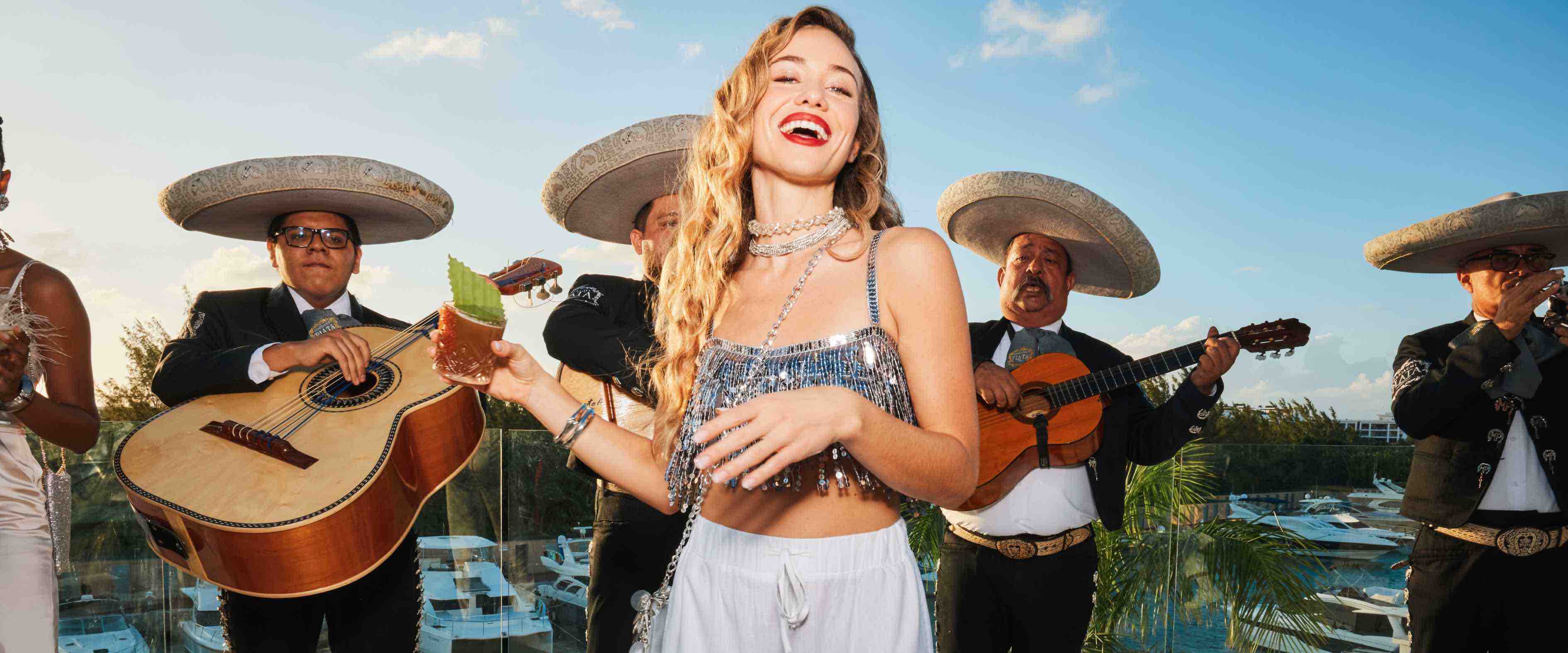 woman with a drink in her hand in front of a band on the beach