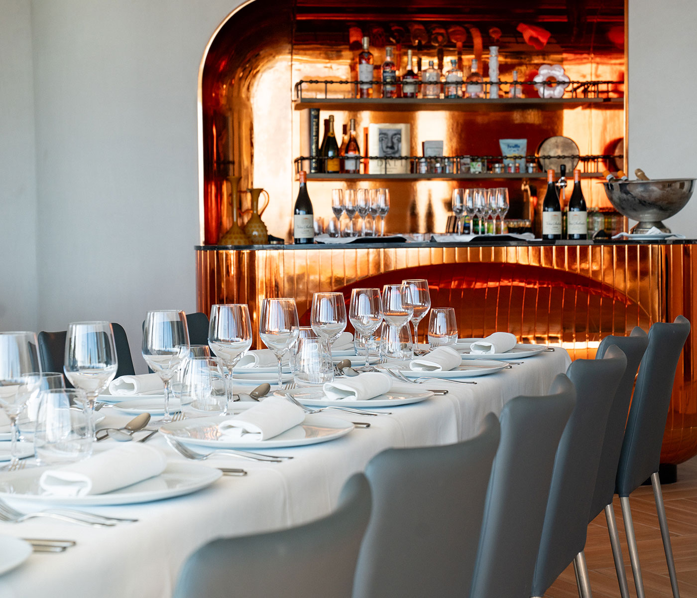 A long table set for a meal with a copper metallic statement bar behind it