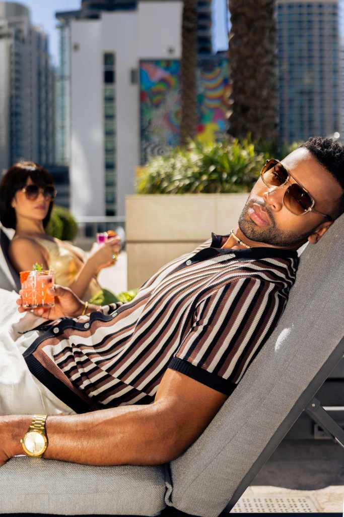stylish couple with cocktails at lounge chairs by the pool 
